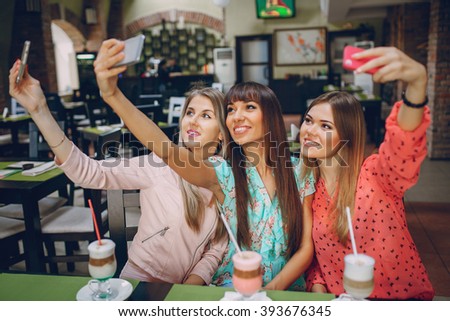 Three beautiful girls in cafes new gadgets are photographed and show photo