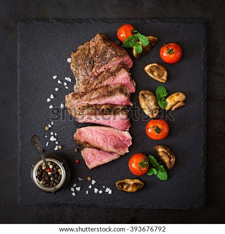Juicy steak medium rare beef with spices and grilled vegetables. Top view Royalty-Free Stock Photo #393676792