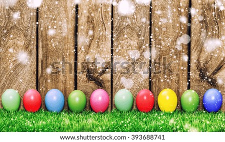Easter eggs in green grass on wooden background with light leaks. Retro style toned picture