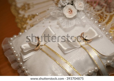 gold wedding rings lie on a decorative pillow