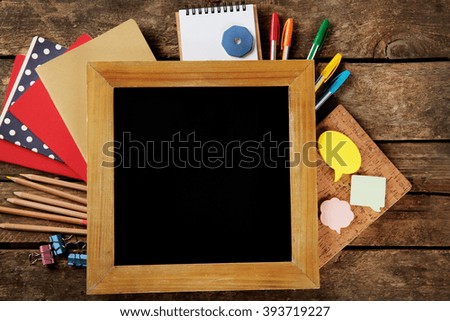 Small school blackboard with stationery on wooden background