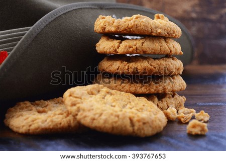 Anzac Day Australian Army slouch hat with stack of traditional Anzac biscuits on dark vintage wood background, closeup.