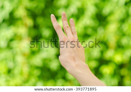 Spring and nature theme: man's hand showing gesture on a background of green grass, first-person view