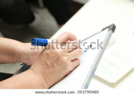 hand is writing on white board 