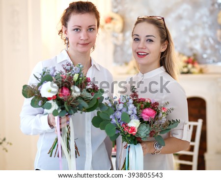 young women holds a bouquet they made. Decor and floral composition on a table.