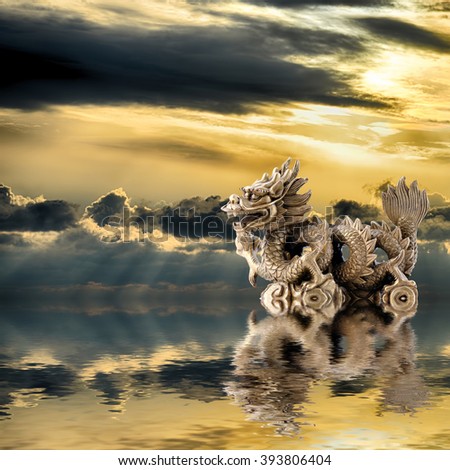 Feng Shui background. Dragon with a pearl is reflected in water at sunrise