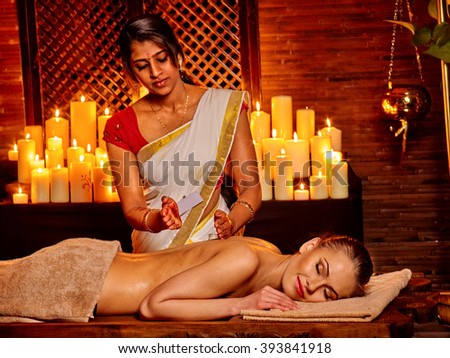 Young woman having oil Ayurveda spa with burning candels. 
