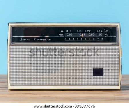 Old retro radio receiver on wooden table and blue background