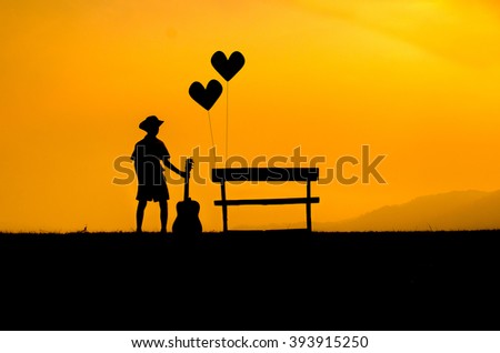 silhouet of oung boy stood beside a chair, alone. sunset