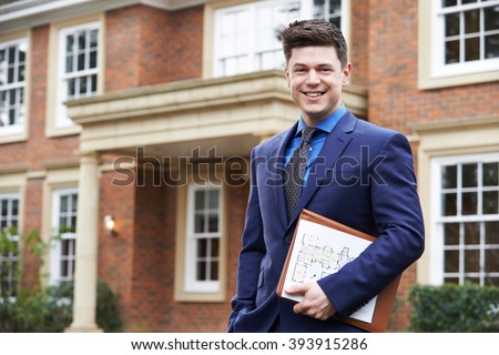 Male Realtor Standing Outside Residential Property Royalty-Free Stock Photo #393915286