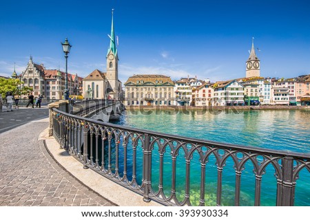 Beautiful view of historic city center of Zurich with famous Fraumunster Church and Munsterbucke crossing river Limmat on a sunny day with blue sky and clouds in summer, Canton of Zurich, Switzerland Royalty-Free Stock Photo #393930334