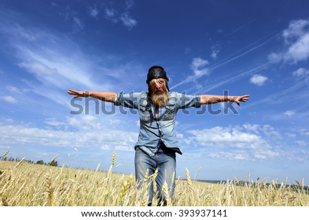 Portrait of an adult man in a wheat field in the aviator image on a sunny day