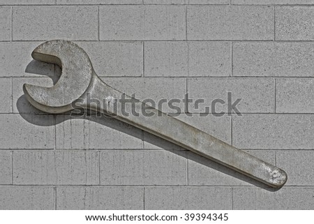 old rusty iron display wrench over cement block wall