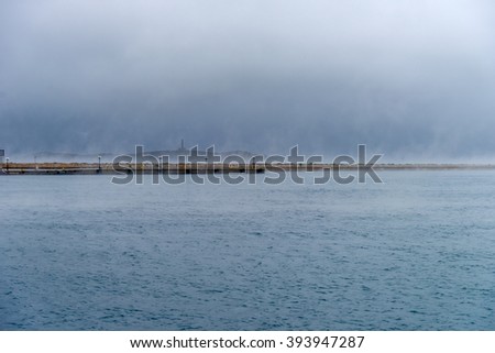 Wild sea during winter. Dramatic scenery with dark clouds and heavy fog above the water.