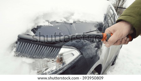 man cleaning car from snow.Transportation, winter, weather, people and vehicle concept - man cleaning snow from car with brush.