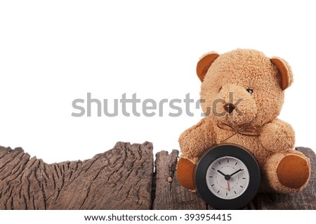 toy teddy bear and black clock on an old wood board isolated on white
