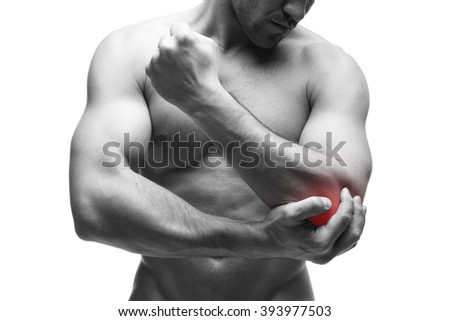 Pain in the elbow. Muscular male body. Handsome bodybuilder posing in studio. Isolated on white background with red dot. Black and white photography
