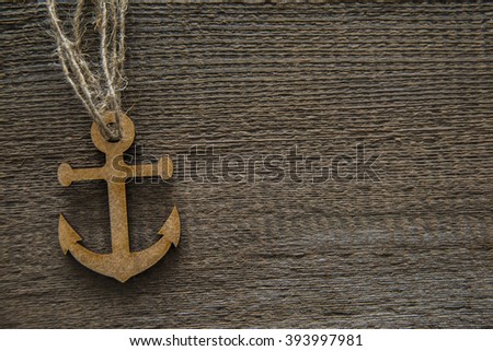 brown or gray  wooden anchor on the background of wooden board. empty copy space for inscription.