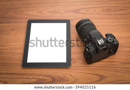 DSLR digital camera and tablet on wooden desk table