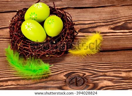 closeup shot of painted easter eggs in decorative nest on wooden background