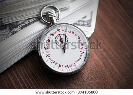 Stopwatch with dollar banknotes on wooden background. Time is money concept