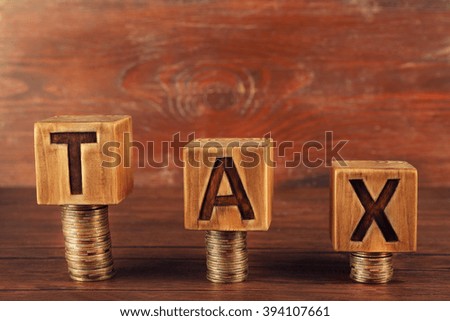 Word tax with stacked coins on wooden background