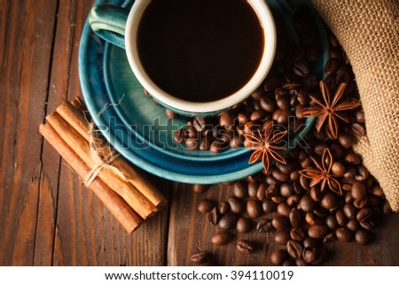 Coffee cup with coffee beans on wooden sacking background with anise and cinnamon