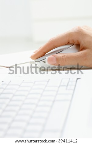 Closeup picture of computer keyboard and female hand using mouse.