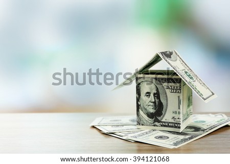 Money house on dollar bills on wooden table, close up