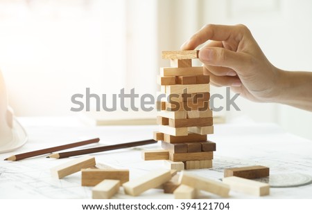 Planning, risk and strategy of project management in business, businessman and engineer gambling placing wooden block on a tower.Business and construction concept. Royalty-Free Stock Photo #394121704