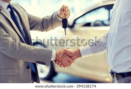 auto business, car sale, deal, gesture and people concept - close up of dealer giving key to new owner and shaking hands in auto show or salon Royalty-Free Stock Photo #394138174