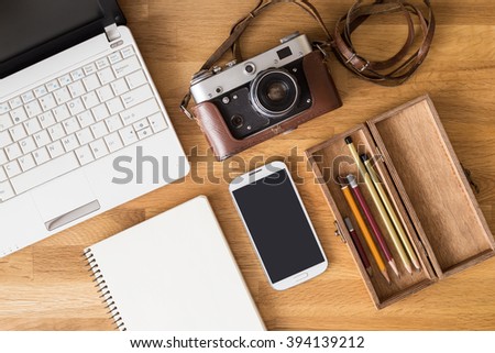Mock up of photographer desk with laptop, note, phone, camera and pencils in wooden box. Top view image of designer or traveler workplace