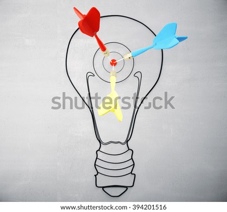 Goal concept with light bulb and darts on concrete wall
