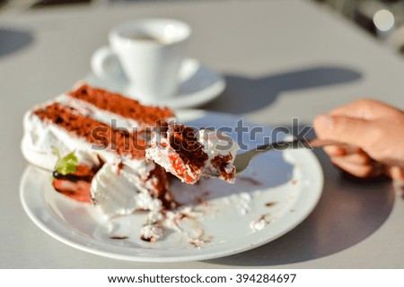 Closeup on person hand and delicious chocolate cake on sunny outdoors background