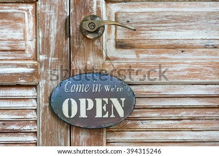 Wooden door with brass handle knob and hang Welcome sign in vintage style.