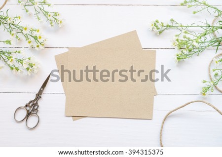 Blank greeting card with brown envelop and daisy flowers on white wooden table with vintage tone