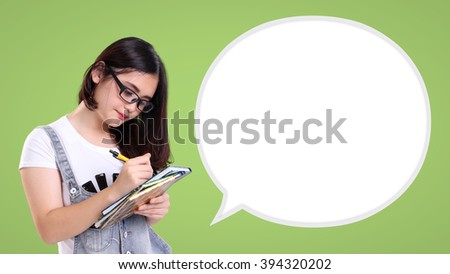 Cute school girl writing on a book, with a blank speech balloon for copy space beside her, over green background. Education concept in comic style design ready to use Royalty-Free Stock Photo #394320202