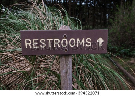 Restrooms sign with an arrow points toward a nature trail that leads to the bathroom at a campground in Oregon.