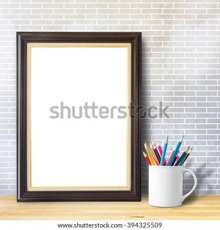 Poster mock up template with pencils in cup on wooden table over brick white wall , clipping path inside