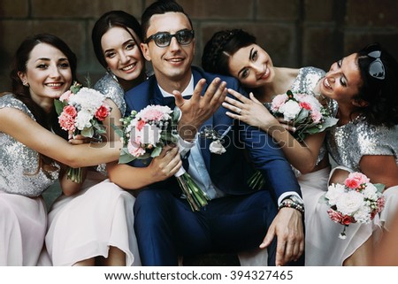 Handsome groom posing with fun beautiful bridesmaids