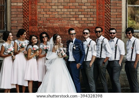Cheerful & fun groom with bride, bridesmaids & groomsmen posing outdoors