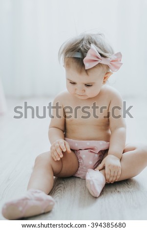Cute baby girl playing in a white room in the morning