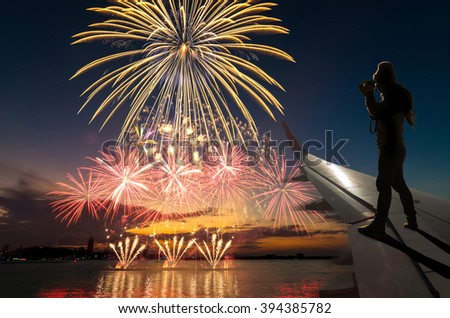 silhouette of photographer taking photo on airplane wing which can see Fantastic festive colorful fireworks, Challenge and success business concept