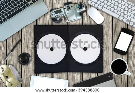 Top view of empty disk with cover and office accessory on wooden background, technology equipment mockup, flat lay