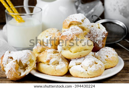 Choux pastry cake eclairs or profiteroles with whipped cream and powdered sugar selective focus