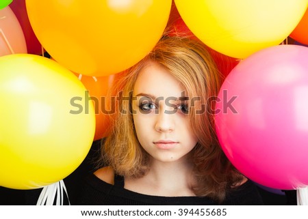 Studio portrait of beautiful teenage Caucasian blond girl with colorful balloons