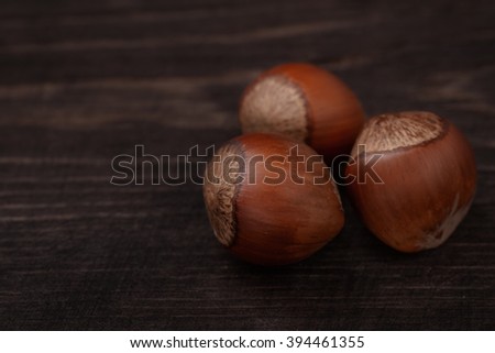 Three  hazelnuts on dark wood background