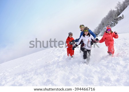 Family of 4 running down in snowy slope