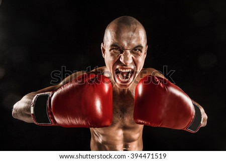 The young man kickboxing on black  with screaming face