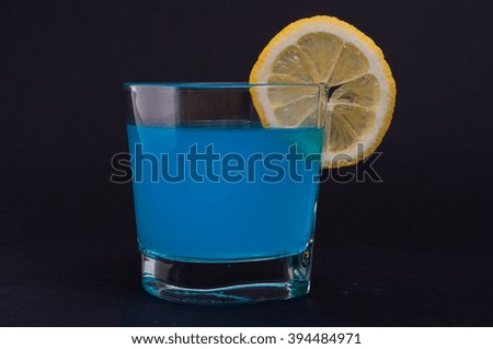 Photo of blue cocktail with lemon against black background